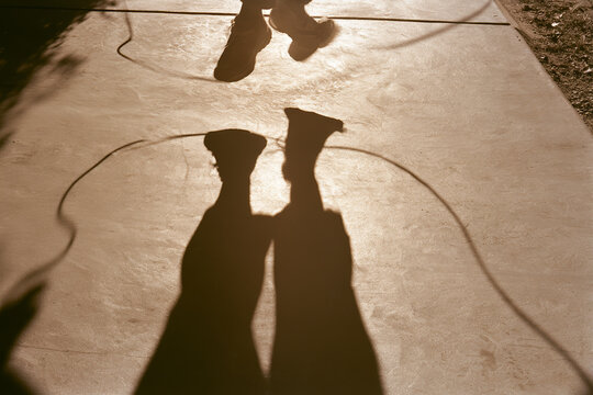 Minimalist jumping rope shadow with intense action low angle hard sunlight sepia