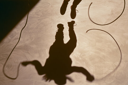 Minimalist jumping rope shadow with intense action low angle hard sunlight sepia