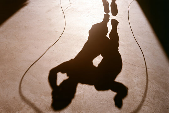 Minimalist jumping rope shadow with intense action low angle hard sunlight sepia