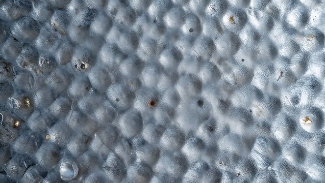 A captivating close-up of an uneven and deeply textured hammered metal sheet.