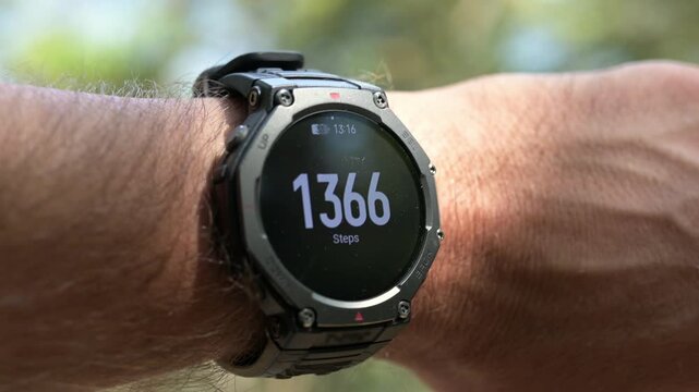 Smartwatch displaying daily step count tracking on a man's wrist outdoors