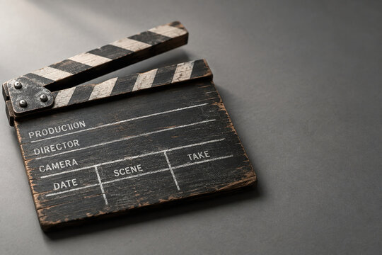 Weathered wooden film clapperboard on grey surface for filmmaking and cinema production concept