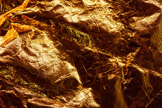 Close-up of a vibrant golden crumpled metallic foil with a textured surface.