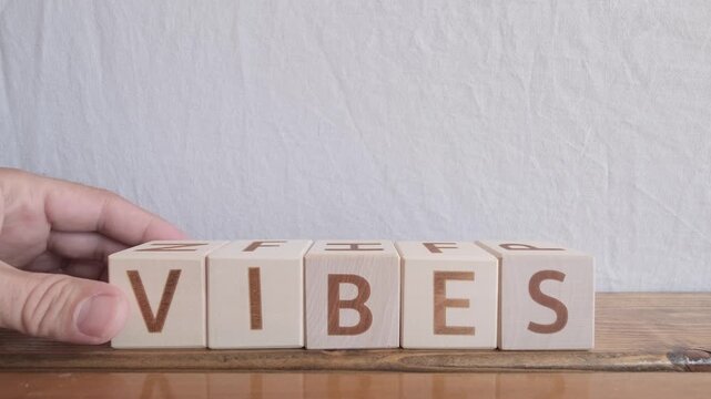 motivational word Vibes, laying out by hand from letters on wooden cubes, slow motion
