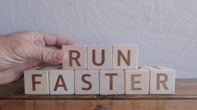 motivational word Run faster, laying out by hand from letters on wooden cubes, slow motion
