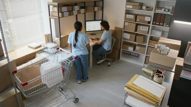 Young multiethnic colleagues packing boxes and processing shipping orders in warehouse office. Footage fits logistics commercials, retail campaigns, online store management promos
