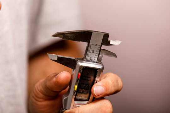 Close-up of a hand holding and operating a modern digital caliper for accuracy.