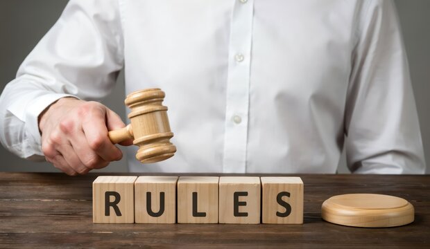 Judge holding a wooden gavel above wooden blocks with the word rules, concept of law and justice