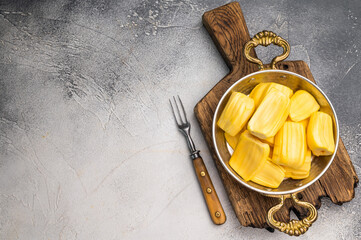 Sweet, golden jackfruit pods (bulbs) in a traditional metal bowl with a fork. Exotic tropical snack or dessert with copy space © Mironov