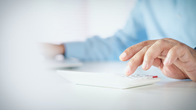 Businessman using a white calculator on desk with copy space, concept of financial calculation, business accounting, tax calculation, budget planning, and cost analysis.