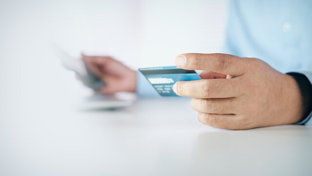 Businessman holding a credit card for online shopping and payment on white desk with copy space, concept of e-commerce, digital banking, financial transaction, and secure payment.