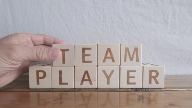 motivational word Team player, laying out by hand from letters on wooden cubes, slow motion
