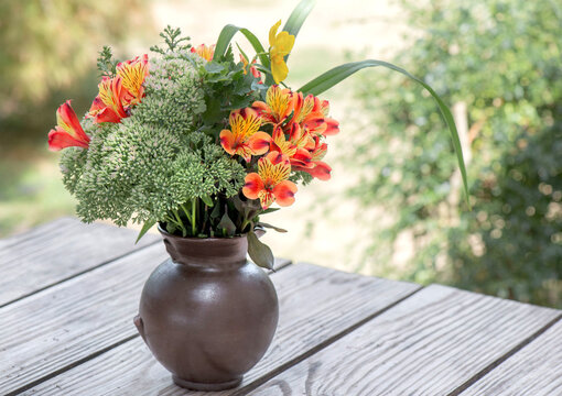bouquet of beautiful flowers orange, red and yellow Alstroemeria Peruvian lily in a vase on a table in garden
