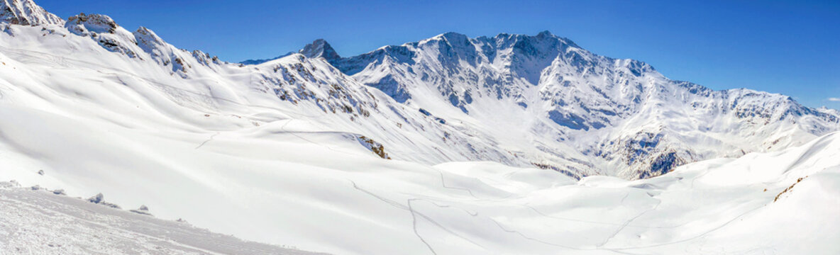 off-piste in the Tarentaise ski resort, the Bellecote massif. Snowy alpine mountain peak under blue sky