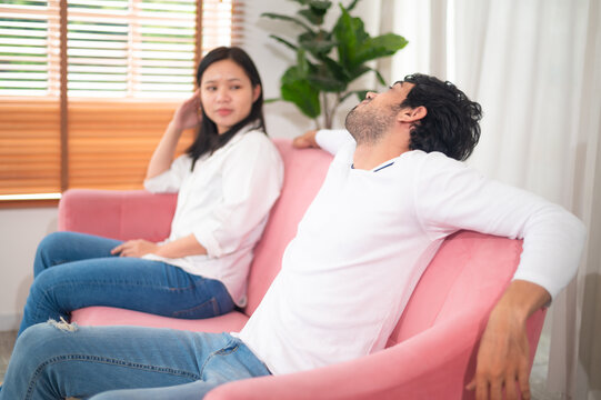 A couple sits in a modern living space, expressing emotions during a tense conversation, capturing the complexity of relationships and communication.