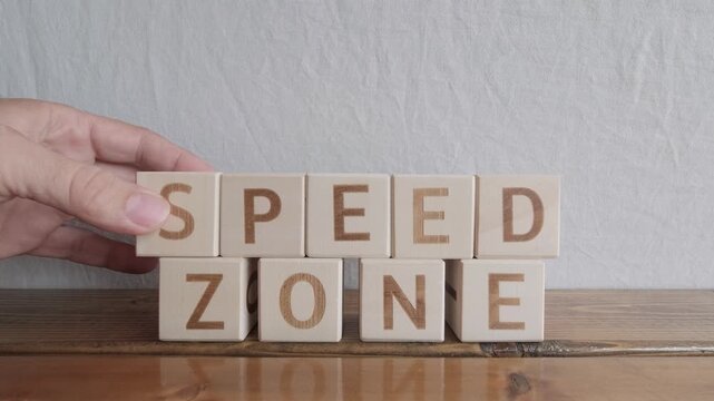 motivational word Speed zone, laying out by hand from letters on wooden cubes, slow motion
