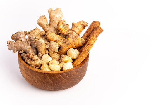 Wooden bowl with spice ingredients including ginger, turmeric, candlenut, cinnamon and copy space isolated on white background, ideal for cooking ads, herbal promos and spice packaging banners