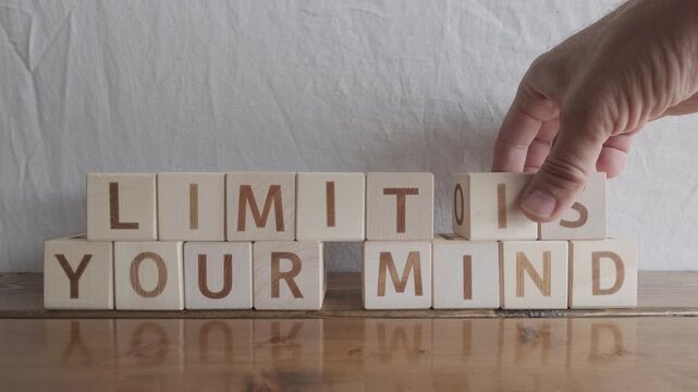 motivational word Limit is your mind, laying out by hand from letters on wooden cubes, slow motion
