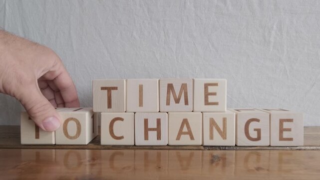 motivational word Time to change, laying out by hand from letters on wooden cubes, slow motion

