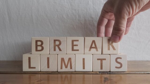 motivational word Break limits, laying out by hand from letters on wooden cubes, slow motion
