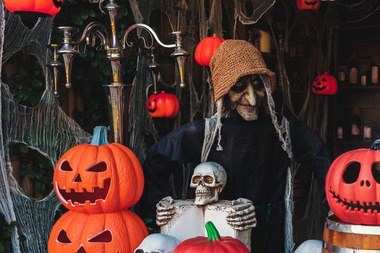 Halloween witch prop surrounded by carved jack o lantern pumpkins and skulls decoration. creepy Halloween witch prop, Halloween party decor, spooky event marketing, and seasonal holiday background.