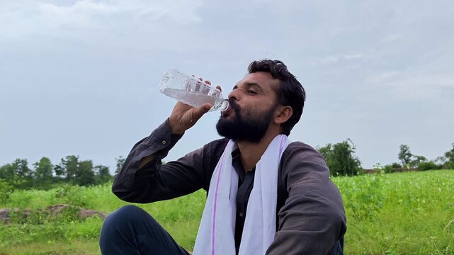 Thirsty indian farmer drinking water from bottle