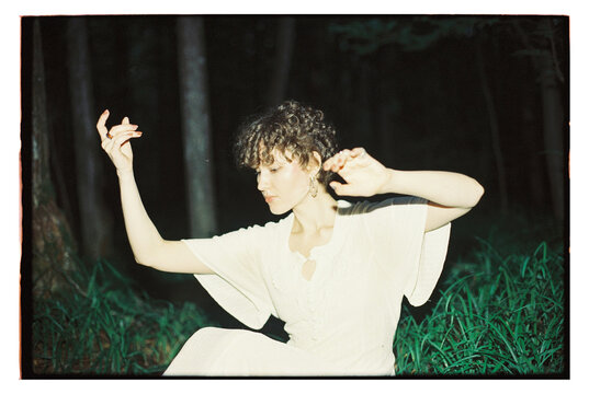 Girl dancing in the forest at night while wearing a white dress