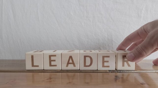motivational word Leader, laying out by hand from letters on wooden cubes, slow motion
