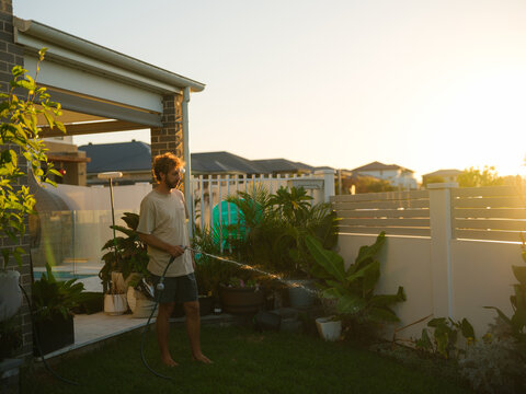 Man watering plants in a backyard