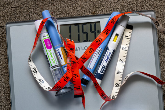 Photo illustration of weight loss injection pens on a weight scale with tape measure.