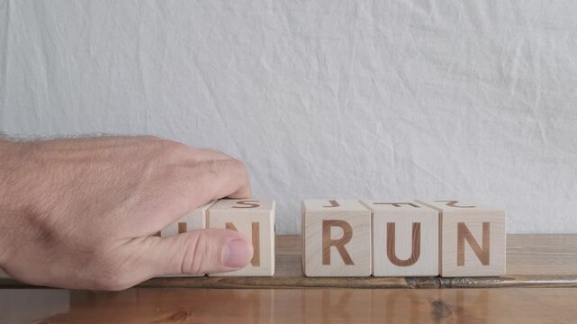 motivational word Run run, laying out by hand from letters on wooden cubes, slow motion

