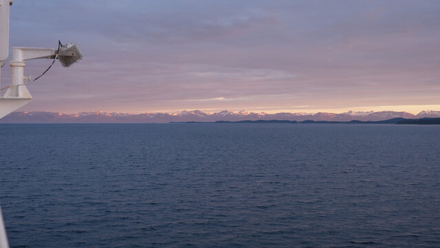 Breathtaking Alaska mountain glacier range view seen from outdoor deck of cruise ship liner sailing the Inside Passage transit with spectacular landscape scenery during sunset