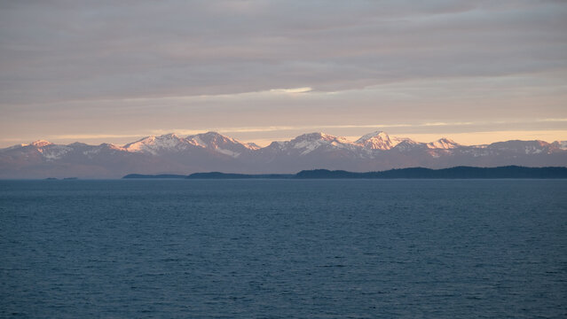 Breathtaking Alaska mountain glacier range view seen from outdoor deck of cruise ship liner sailing the Inside Passage transit with spectacular landscape scenery during sunset