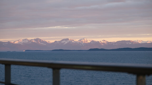 Breathtaking Alaska mountain glacier range view seen from outdoor deck of cruise ship liner sailing the Inside Passage transit with spectacular landscape scenery during sunset