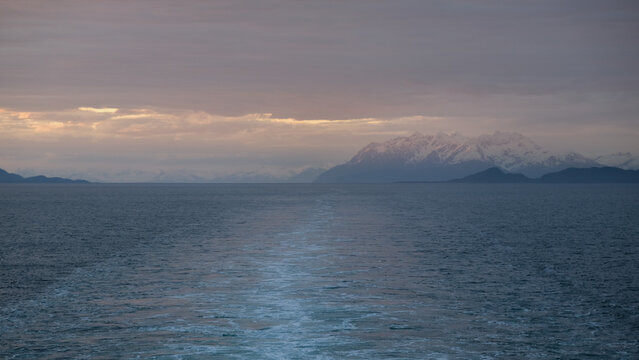 Breathtaking Alaska mountain glacier range view seen from outdoor deck of cruise ship liner sailing the Inside Passage transit with spectacular landscape scenery during sunset