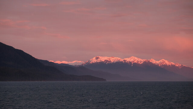 Breathtaking Alaska mountain glacier range view seen from outdoor deck of cruise ship liner sailing the Inside Passage transit with spectacular landscape scenery during sunset