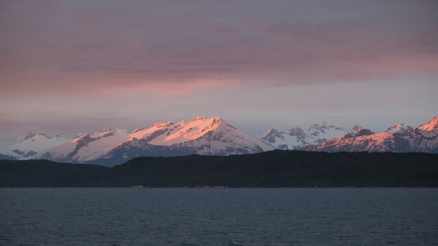 Breathtaking Alaska mountain glacier range view seen from outdoor deck of cruise ship liner sailing the Inside Passage transit with spectacular landscape scenery during sunset