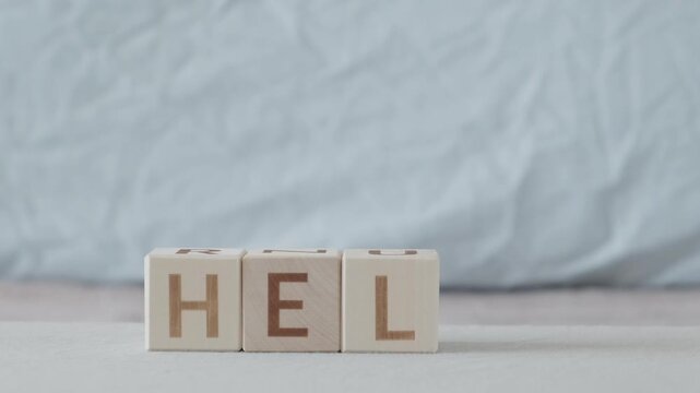 motivational word Help, laying out  by hand from letters on wooden cubes, slow motion