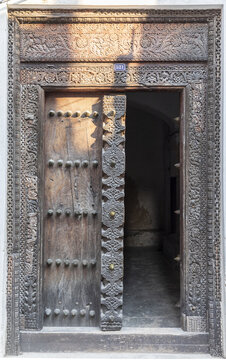 View of an intricately carved traditional wooden door with brass studs in the historic Stone Town of Zanzibar, Mjini Magharibi Regio, Tanzania.