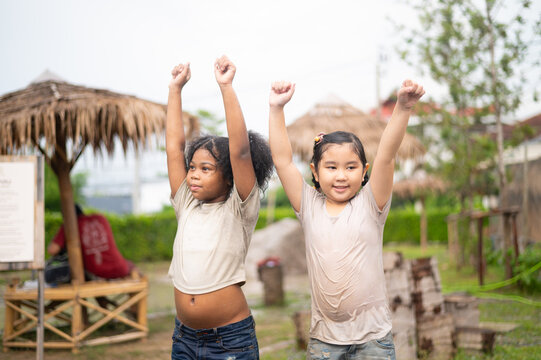 Two joyful children celebrate in nature, expressing enthusiasm and friendship, showcasing youthful energy and happiness in a vibrant outdoor setting.