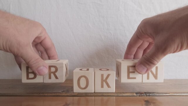 motivational word Broken ok, laying out by hand from letters on wooden cubes, slow motion
