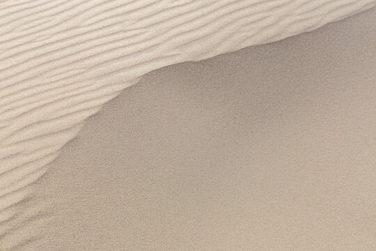 View of the wind-swept sand dunes at Rabjerg Mile, showcasing intricate ripple patterns and textures in the sand in Skagen, Jutland, Denmark.