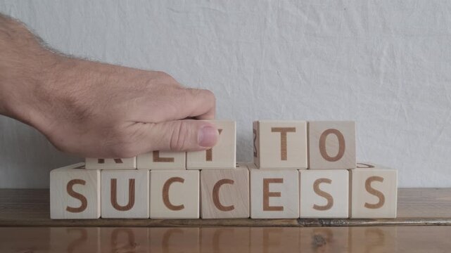 motivational word Key to success, laying out by hand from letters on wooden cubes, slow motion
