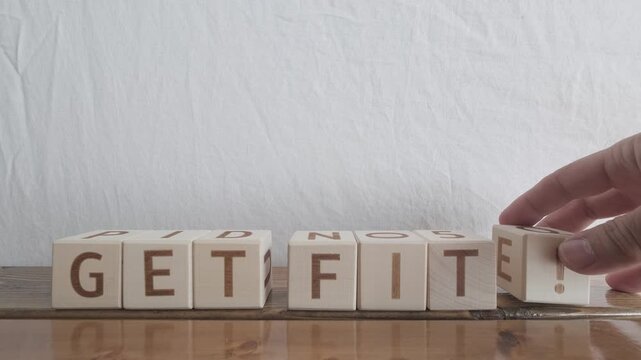 motivational word Get fit!, laying out by hand from letters on wooden cubes, slow motion

