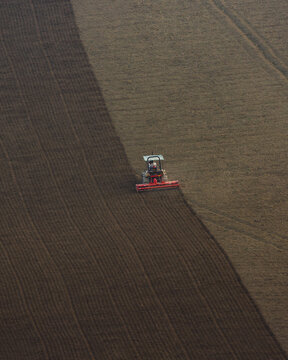 View of a tractor plowing a large field with dark soil in Corridonia, Marche, Italy.