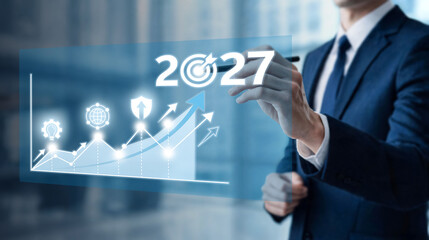 Obraz premium Businessman drawing 2027 target over glowing business growth graph