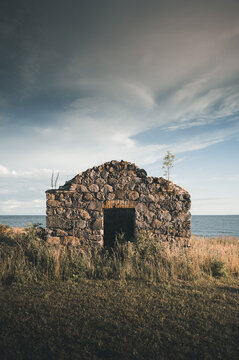View of an old stone ruin by the sea with dry grass and a cloudy sky in Virtsu, Parnu maakond, Estonia.