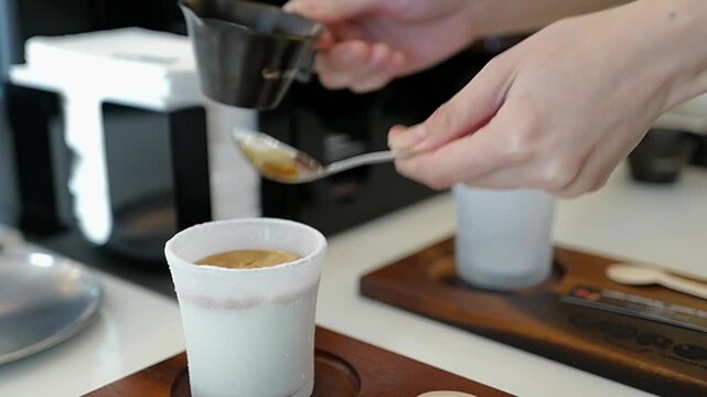 Close-up of a woman barista pouring black coffee shot to the glass with cold fresh milk. Process making Dirty Latte Coffee Creamy Cup of 'LORO SPECIALTY COFFEE'.