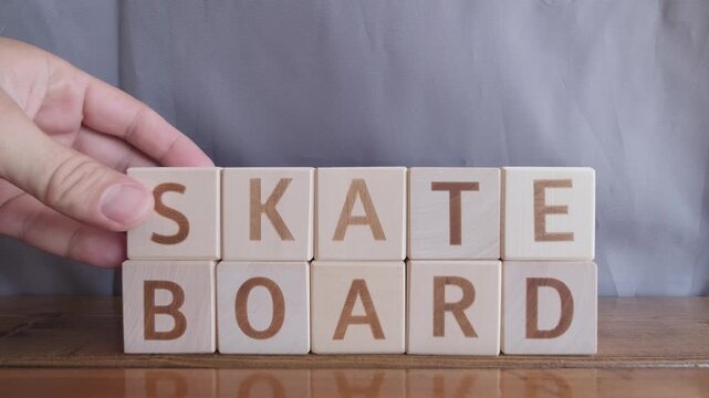 motivational word Skate board, laying out by hand from letters on wooden cubes, slow motion
