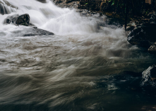 View of a rushing waterfall cascading over dark rocks into a turbulent stream in Jos East, Plateau, Nigeria.